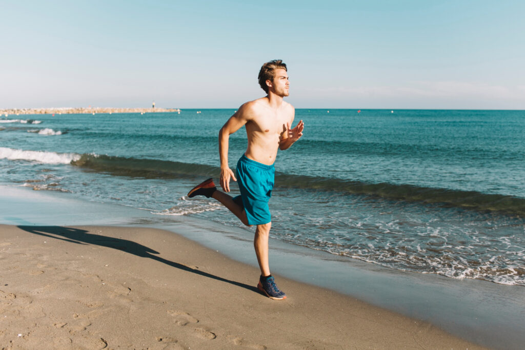 Runner che corre sulla sabbia, allenando equilibrio e muscoli stabilizzatori