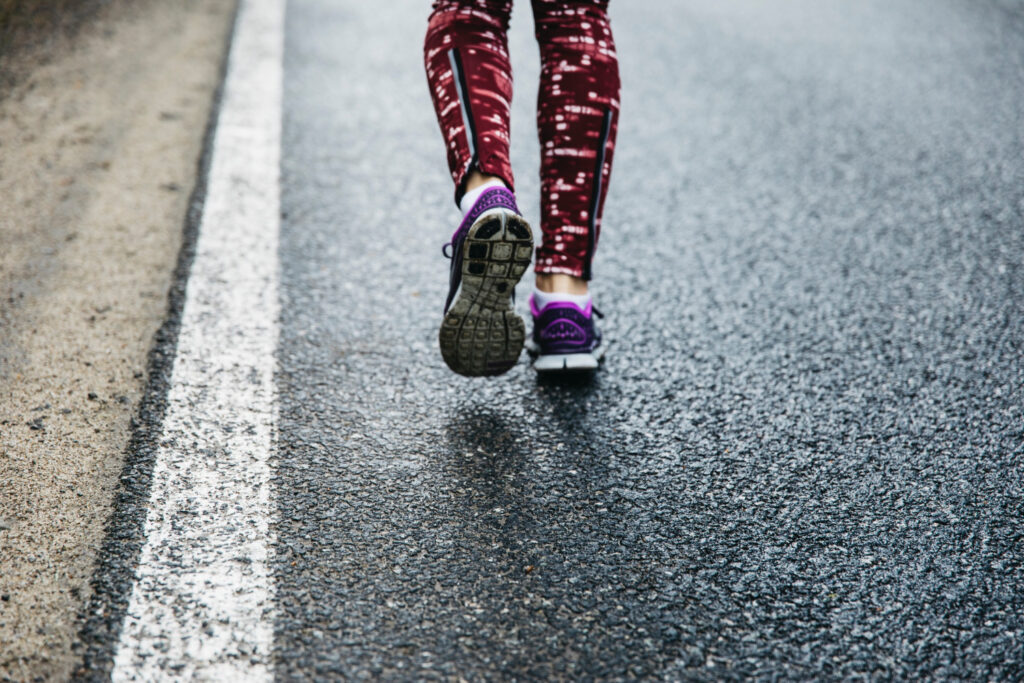 Piedi con scarpe da corsa su asfalto, simbolo di comfort e prestazioni durante la corsa urbana