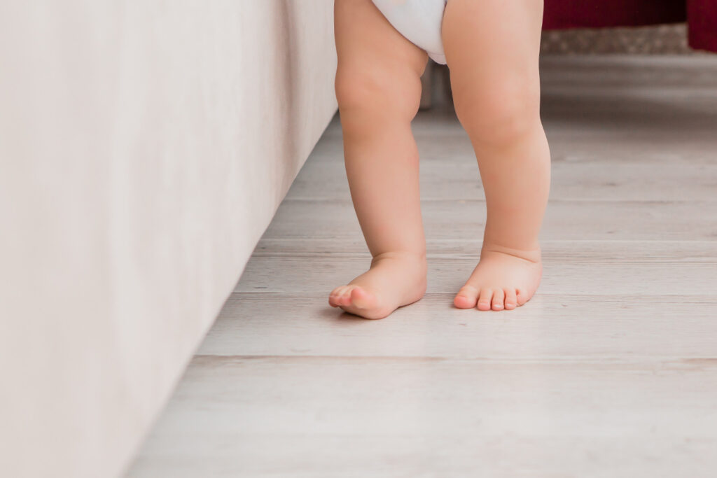 Piedini scalzi di un bambino che cammina su un pavimento di casa, esplorando liberamente l'ambiente
